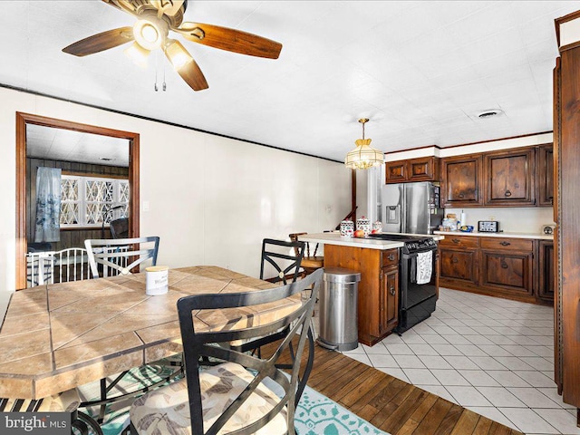 kitchen with a center island, black range with electric cooktop, light countertops, light wood-style flooring, and stainless steel fridge