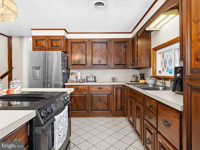 kitchen featuring visible vents, black electric range oven, a sink, stainless steel fridge, and light countertops