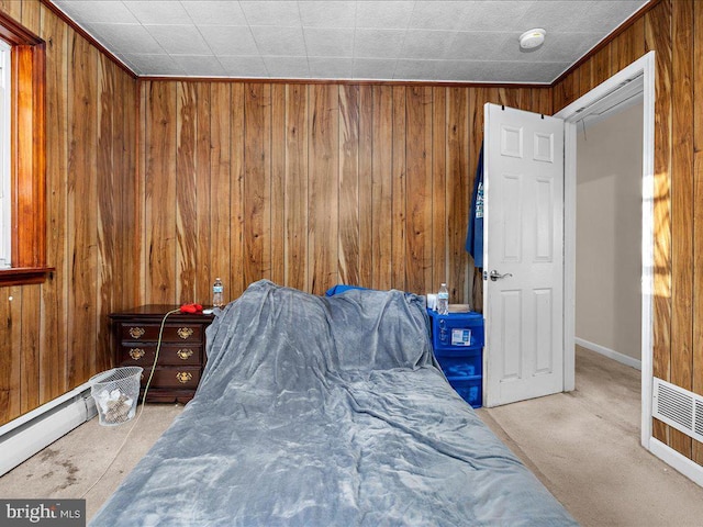 bedroom with a baseboard heating unit, wood walls, and carpet floors