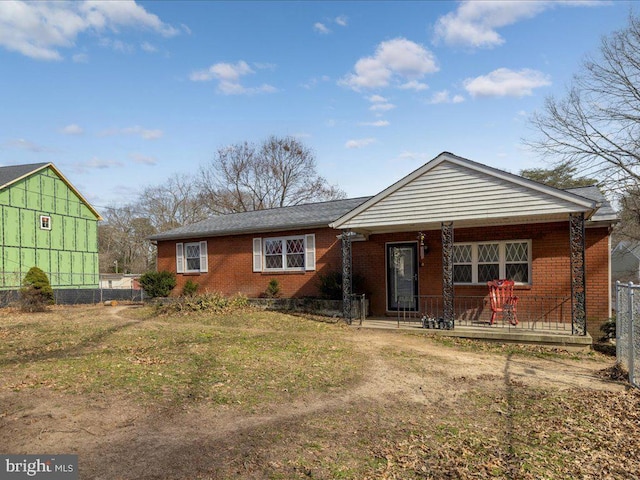 view of front of home with brick siding, a porch, and fence