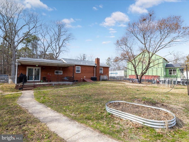 back of property with a yard, brick siding, a chimney, and fence