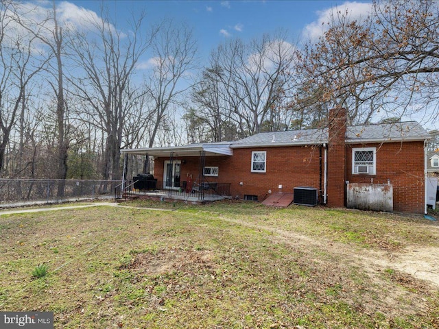 rear view of property with brick siding, central air condition unit, a yard, and fence