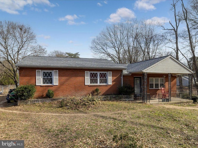 ranch-style home featuring brick siding, a front yard, and roof with shingles