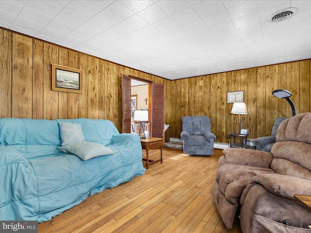 living room with visible vents, baseboard heating, wood walls, and hardwood / wood-style flooring