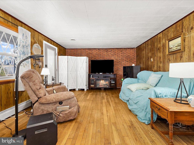 living room featuring a baseboard radiator, hardwood / wood-style floors, a fireplace, and wood walls