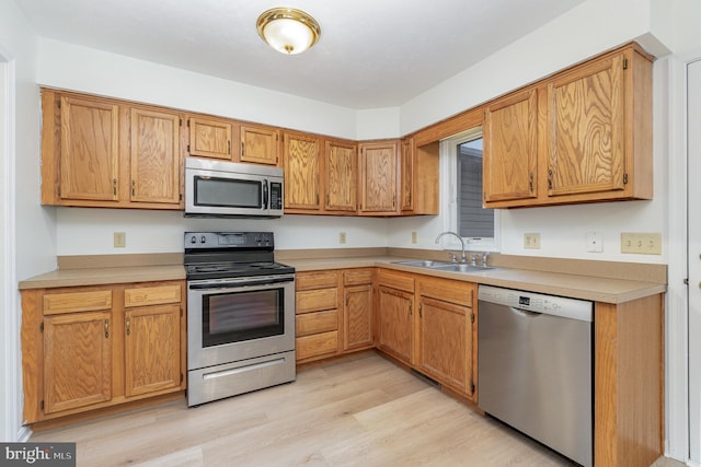 kitchen featuring a sink, light wood-type flooring, appliances with stainless steel finishes, and light countertops