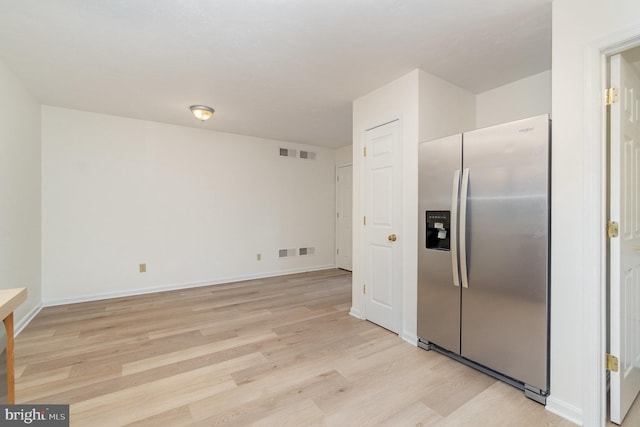 kitchen with light wood finished floors, visible vents, baseboards, and stainless steel fridge with ice dispenser