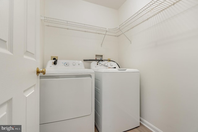 laundry area with wood finished floors, baseboards, washing machine and dryer, and laundry area