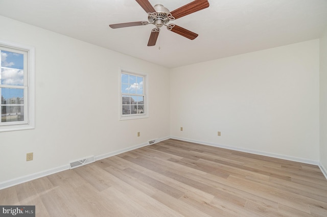 spare room featuring baseboards, visible vents, and light wood finished floors