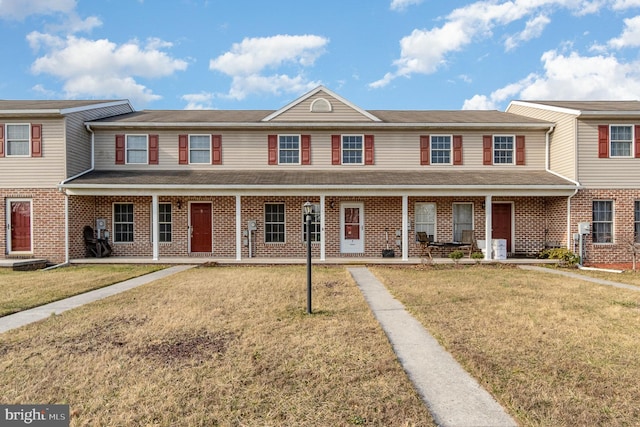 multi unit property with brick siding, covered porch, and a front yard