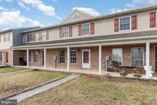 townhome / multi-family property featuring a porch, brick siding, and a front yard