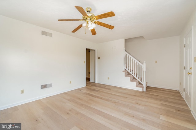 unfurnished living room with stairway, baseboards, visible vents, and light wood-style flooring