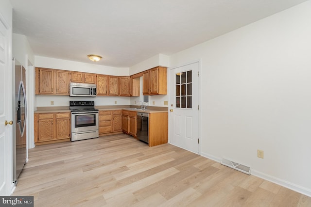 kitchen with visible vents, a sink, stainless steel appliances, light countertops, and light wood-type flooring