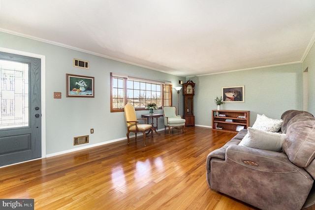 living area featuring visible vents, baseboards, wood finished floors, and crown molding