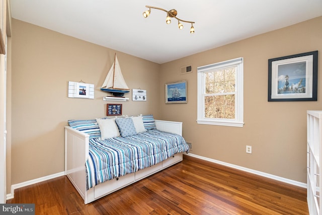 bedroom featuring wood finished floors, visible vents, and baseboards