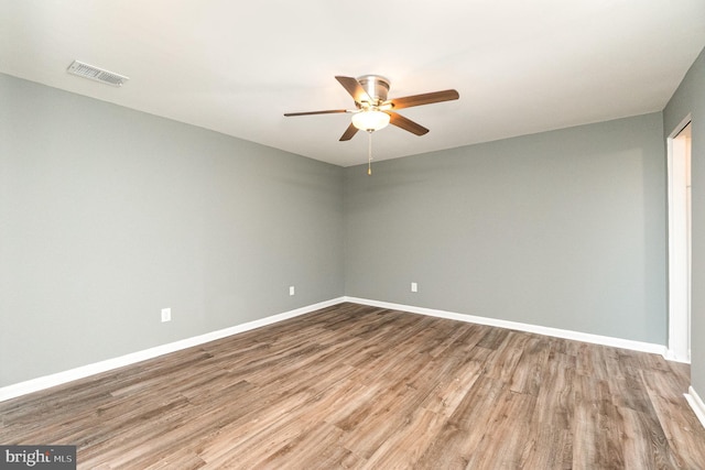 spare room with visible vents, baseboards, wood finished floors, and a ceiling fan