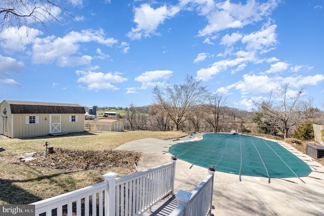 view of pool with an outbuilding, a patio area, a storage shed, and a covered pool