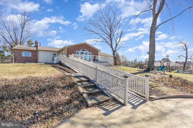 view of front of home with a playground, fence, brick siding, and a chimney