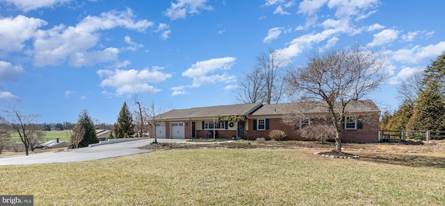 ranch-style house featuring brick siding, driveway, an attached garage, and a front yard