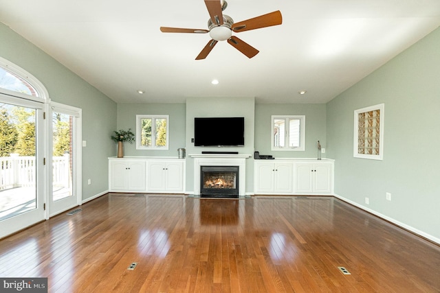 unfurnished living room with visible vents, hardwood / wood-style flooring, a fireplace with flush hearth, and vaulted ceiling