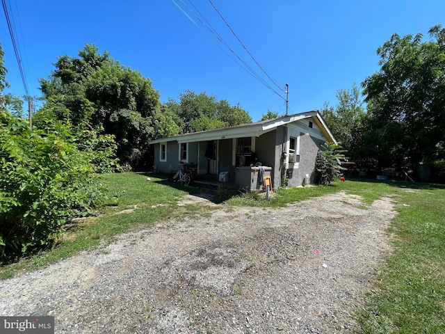 view of front facade with driveway, covered porch, and a front yard