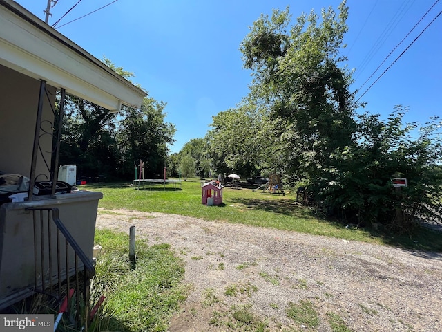 view of yard with a playground and a trampoline