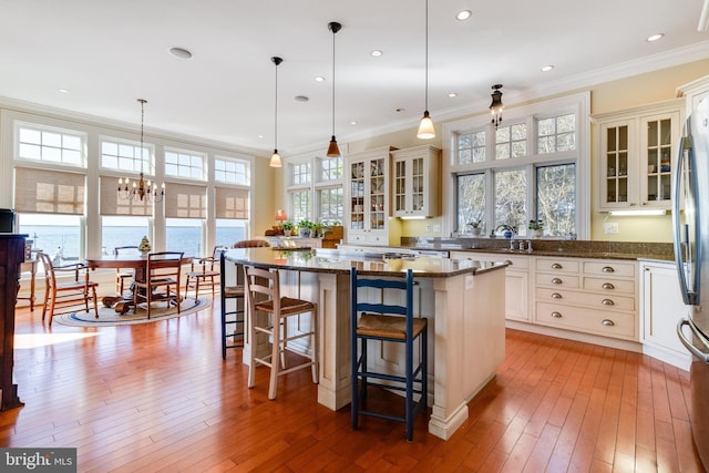 11520 Magnolia Ct, Issue, MD 20645 - kitchen featuring healthy amount of natural light, a breakfast bar area, wood-type flooring, crown molding, and a kitchen island