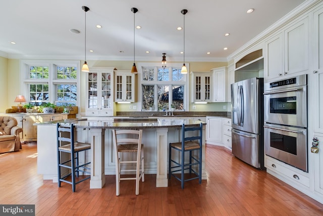 11520 Magnolia Ct, Issue, MD 20645 - kitchen featuring appliances with stainless steel finishes, healthy amount of natural light, glass insert cabinets, a breakfast bar area, and ornamental molding
