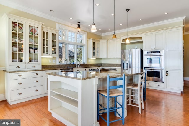 11520 Magnolia Ct, Issue, MD 20645 - kitchen featuring open shelves, appliances with stainless steel finishes, a center island, light wood-type flooring, and ornamental molding