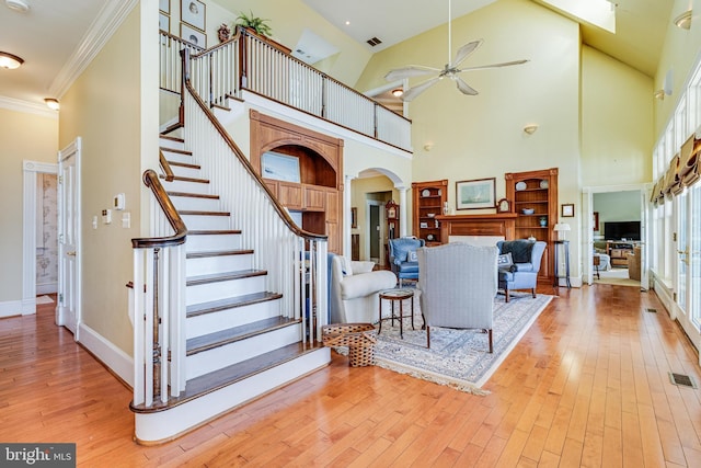 11520 Magnolia Ct, Issue, MD 20645 - living room featuring arched walkways, ceiling fan, a high ceiling, light wood-style floors, and stairway