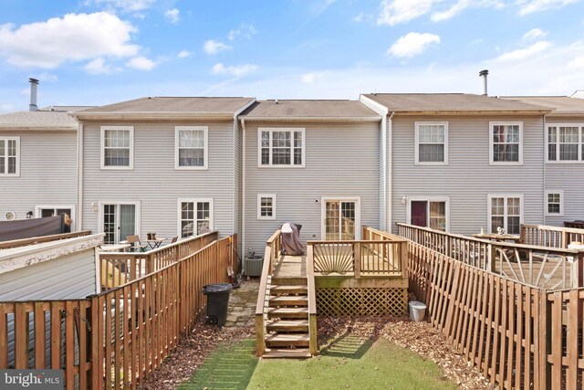 rear view of property featuring a deck, cooling unit, and fence