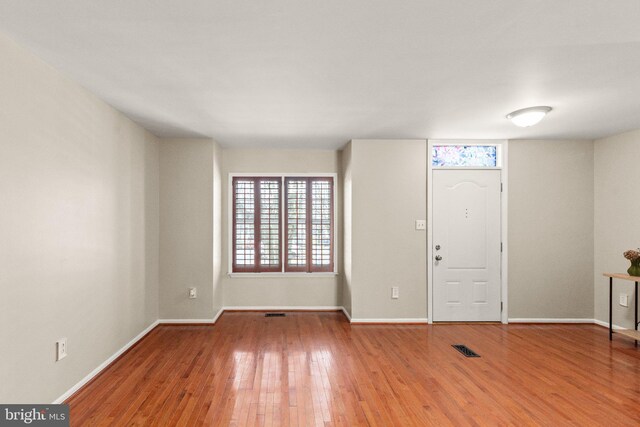 foyer with hardwood / wood-style floors, baseboards, and visible vents