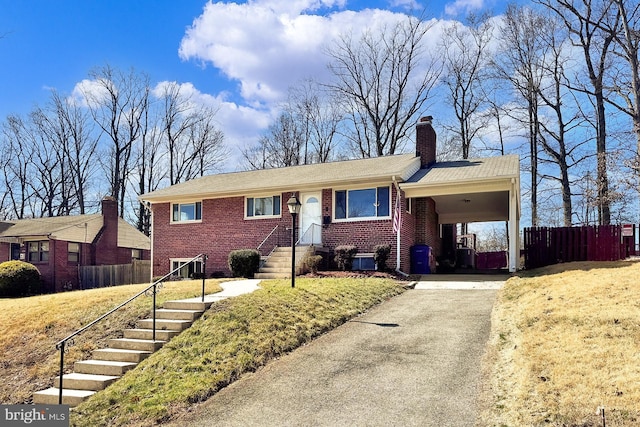 ranch-style house featuring brick siding, driveway, fence, and a carport