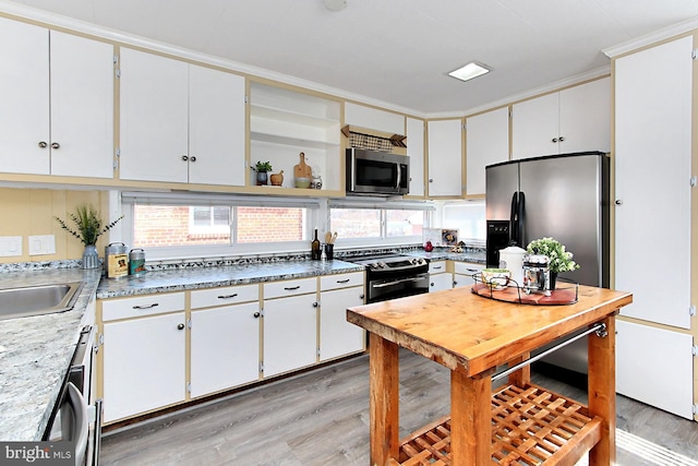 kitchen with light wood-style flooring, appliances with stainless steel finishes, white cabinets, and open shelves