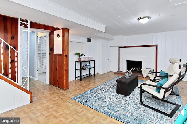 living area with wooden walls, a fireplace, and visible vents