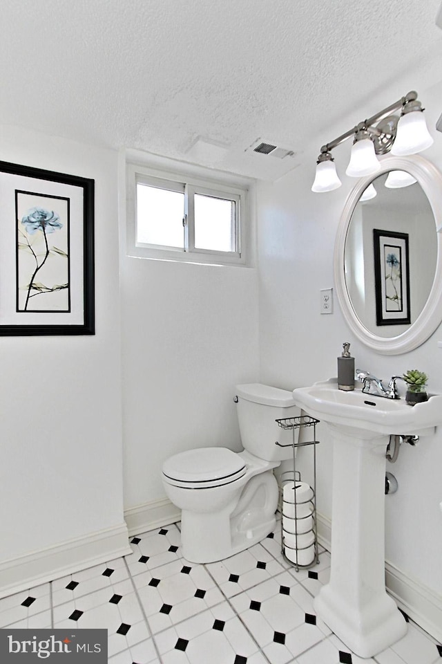 bathroom with baseboards, visible vents, a sink, a textured ceiling, and toilet