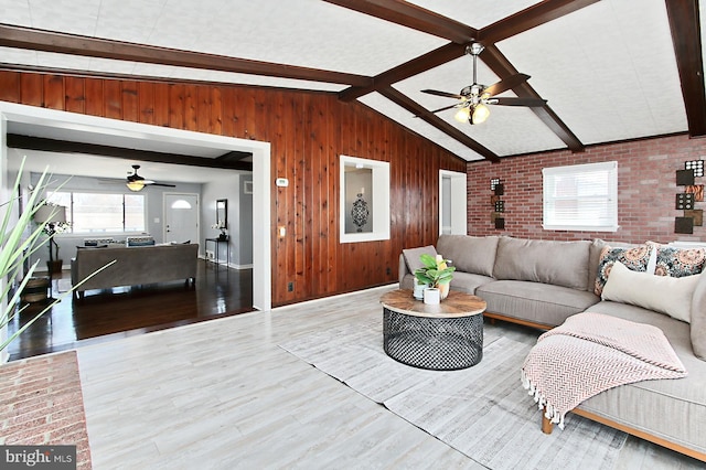 living area with wooden walls, vaulted ceiling with beams, wood finished floors, and brick wall