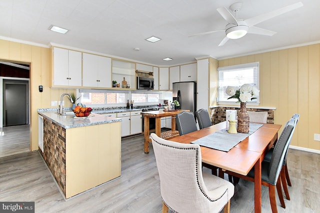 dining area with light wood finished floors, crown molding, and a ceiling fan