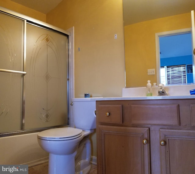 bathroom with toilet, vanity, and bath / shower combo with glass door