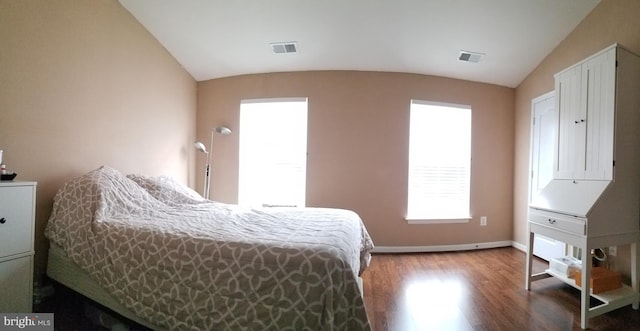 bedroom with visible vents, baseboards, wood finished floors, and vaulted ceiling