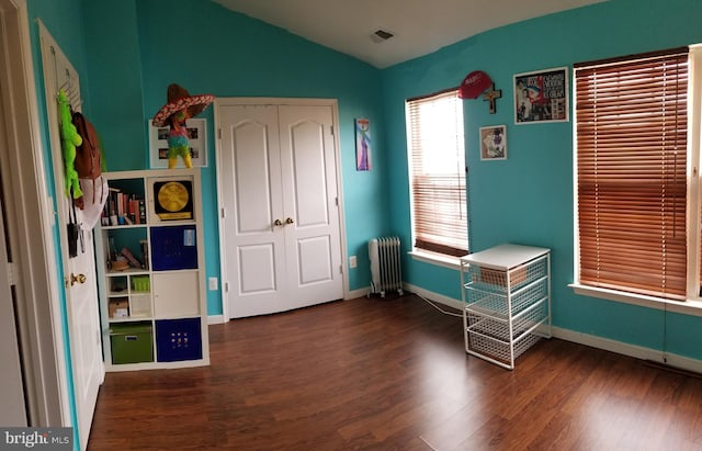 unfurnished bedroom with radiator, wood finished floors, baseboards, vaulted ceiling, and a closet