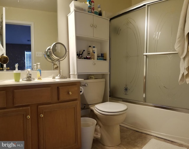 bathroom featuring vanity, toilet, bath / shower combo with glass door, and tile patterned flooring