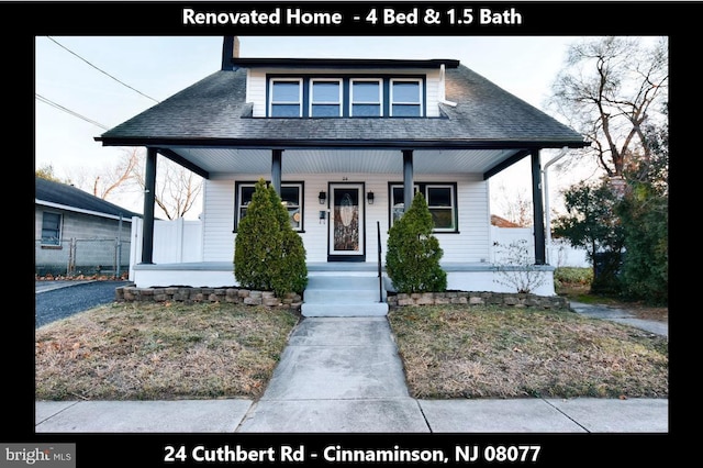 bungalow-style home with a porch, a shingled roof, and fence