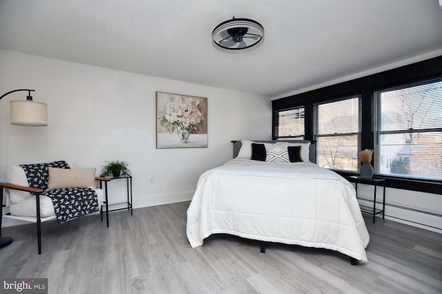 bedroom featuring baseboard heating, baseboards, and wood finished floors