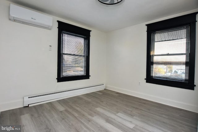 empty room with a baseboard heating unit, wood finished floors, baseboards, and a wall mounted air conditioner