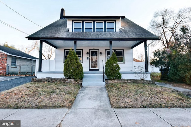 bungalow-style house featuring a chimney, a porch, and a shingled roof