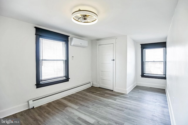 unfurnished room with wood finished floors, a wall mounted air conditioner, baseboards, and a baseboard radiator