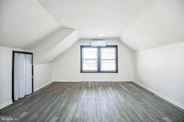 bonus room featuring baseboards, lofted ceiling, dark wood-style flooring, and a wall unit AC