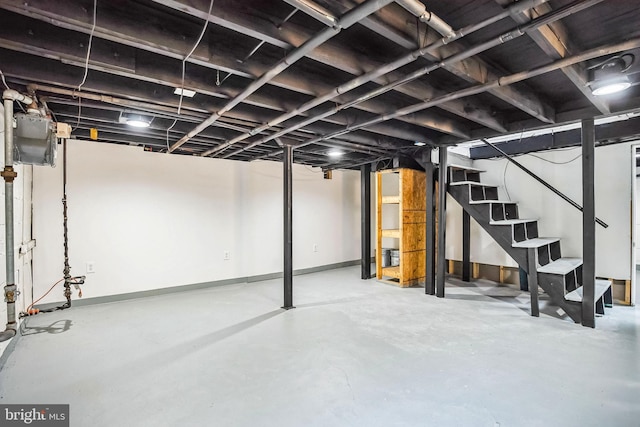 unfinished basement featuring baseboards and stairs