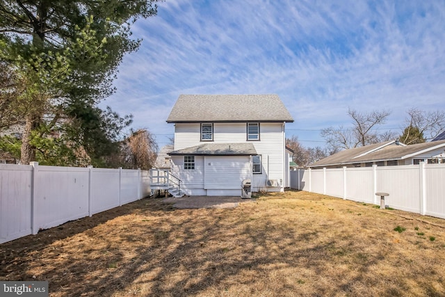 rear view of house with a yard and a fenced backyard